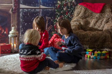 Üç çocuk, erkek kardeşler, Noel gecesi kitap okuyorlar.