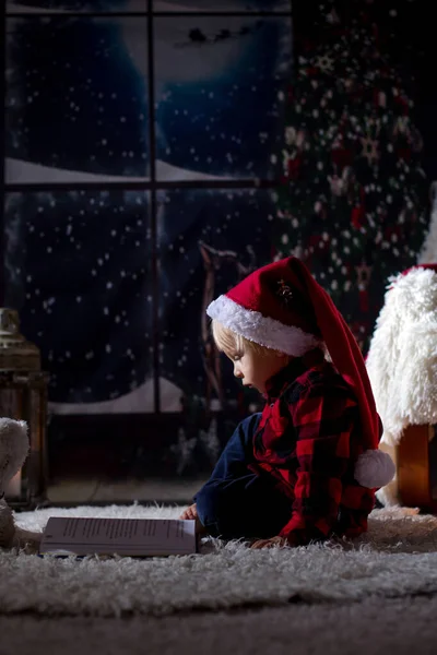 Lieve peuter jongen, lezen boek thuis in de nacht op Kerstmis — Stockfoto