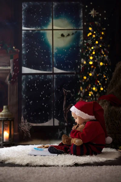 Süßer kleiner Junge, der an Weihnachten abends zu Hause Buch liest — Stockfoto