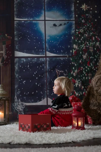 Beautiful toddler boy, opening presents on Christmas night, secr — Stock Photo, Image