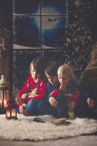 Tre bambini, fratelli maschi, che leggono un libro alla notte di Natale — Foto Stock