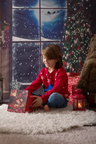 Mooi kind schooljongen, opening cadeautjes op kerstavond — Stockfoto