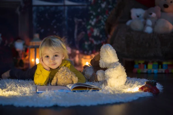 Sweet toddler boy, reading book at home at night on Christmas — Stock Photo, Image