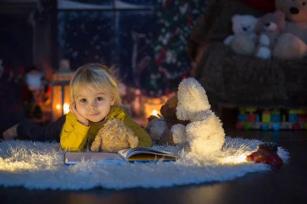 Doux tout-petit garçon, lire le livre à la maison la nuit de Noël — Photo