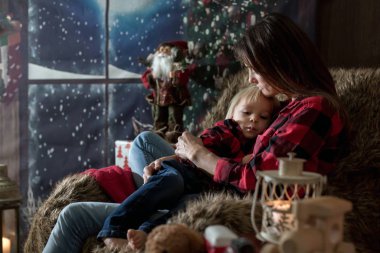 Güzel genç anne, küçük oğluna sarılıyor, rahat bir şekilde oturuyor.