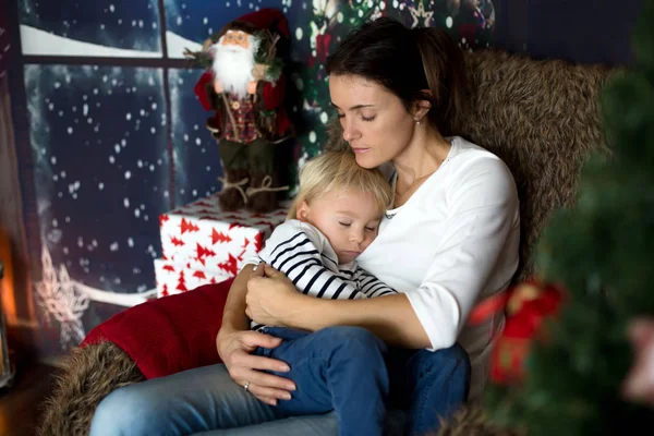 Beautiful young mother, hugging her toddler boy, sitting in cozy — Stockfoto