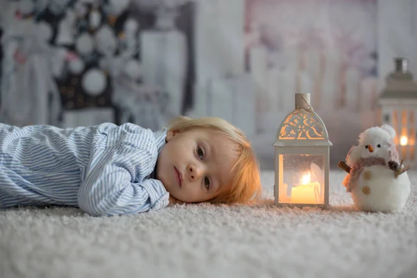 Dolce bambino boylying sul pavimento a casa con candele, waitin — Foto Stock