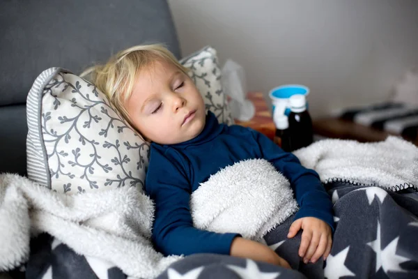 Blond toddler boy, sleeping on the couch in living room, lying d — Stockfoto