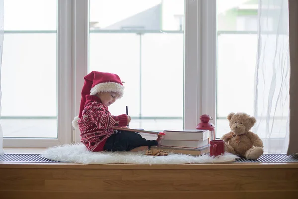 Zoet blond kind, jongen, zitten op venster schild met teddy bea — Stockfoto