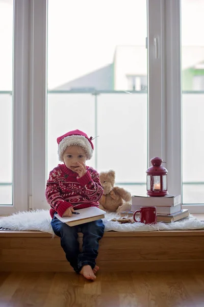 Doux enfant blond, garçon, assis sur le bouclier de la fenêtre avec bea en peluche — Photo