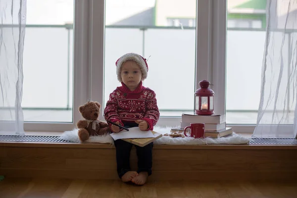 Sweet blonde child, boy, sitting on window shield with teddy bea — Stock Photo, Image