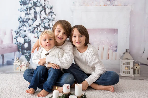 Tres niños, hermanos, leyendo libro en casa por la noche en C —  Fotos de Stock