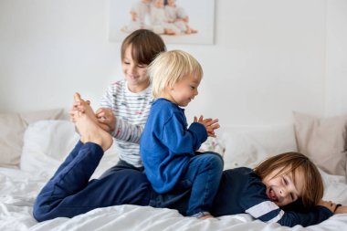 Kardeşler, evde oynuyorlar, ayaklarını gıdıklayıp gülüyorlar. 