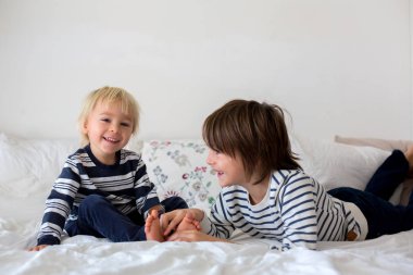 Kardeşler, evde oynuyorlar, ayaklarını gıdıklayıp gülüyorlar. 