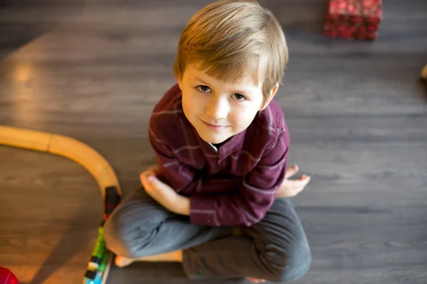 Cute preschool boy, sitting next to christmas tree, playing with — ストック写真