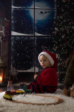 Tatlı çocuk, gece vakti evdeki ahşap trenle oynuyorsun. 