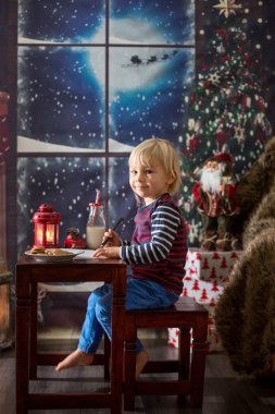 Tatlı sarışın çocuk, Noel Baba 'ya mektup yazıyor.