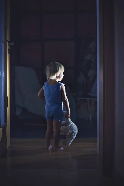 Küçük çocuk, ayaklı oyuncak ayı, koridorun sonunda duruyor. — Stok fotoğraf