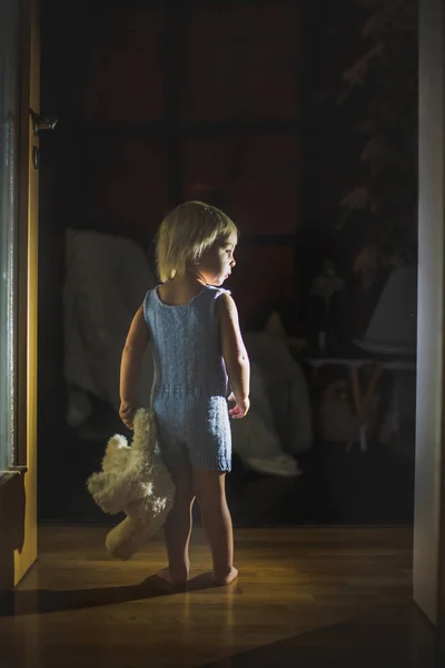 Küçük çocuk, ayaklı oyuncak ayı, koridorun sonunda duruyor. — Stok fotoğraf