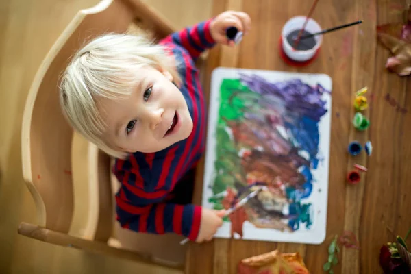 Édes kisgyerek piros kötényes, festés otthon — Stock Fotó