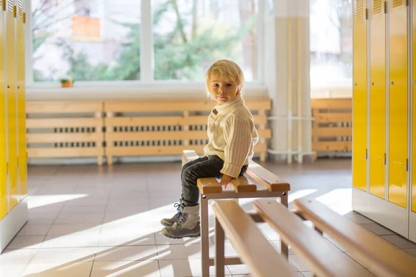 Doce criança loira menino de pé na frente de um armário em kinde — Fotografia de Stock
