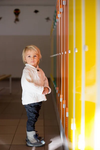 Lief blond peuter jongen staan in de voorkant van een kluisjes in kinde — Stockfoto