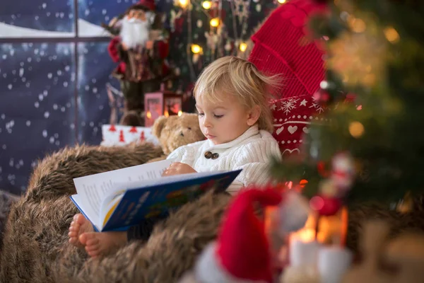 Cute toddler boy, sitting around christmas tree in cozy chair, r — Stock fotografie