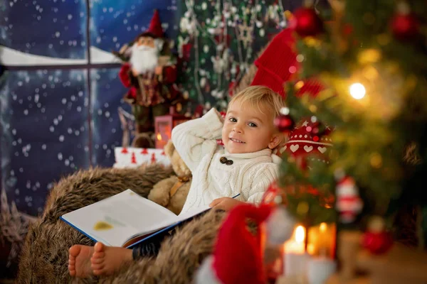 Cute toddler boy, sitting around christmas tree in cozy chair, r — Stockfoto