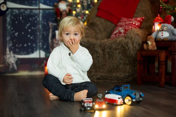PLA 의 바닥에 있는 많은 자동차 장난감 주위에 앉아 있는 귀여운 아기가 — 스톡 사진
