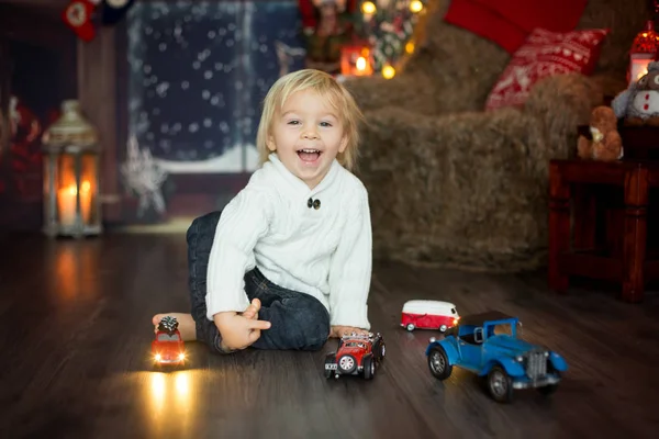 Mignon tout-petit garçon, assis autour de nombreux jouets de voiture sur le sol, pla — Photo