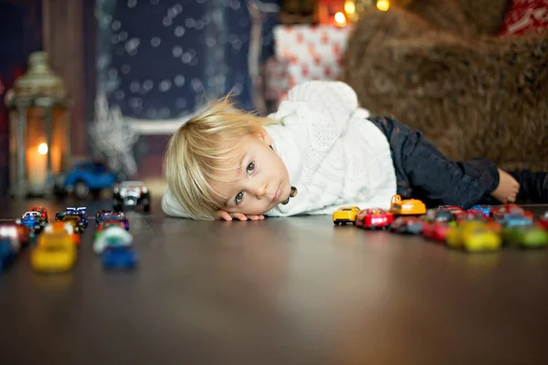 Lindo niño pequeño, sentado alrededor de muchos juguetes de coche en el suelo, pla — Foto de Stock