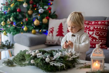 Küçük tatlı sarışın çocuk, evde çelenk yapıyor.