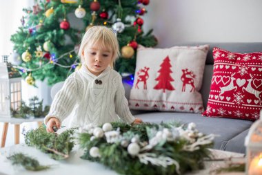 Küçük tatlı sarışın çocuk, evde çelenk yapıyor.