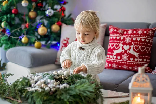 Klein schattig blond peuter jongen, het maken van advent krans thuis — Stockfoto