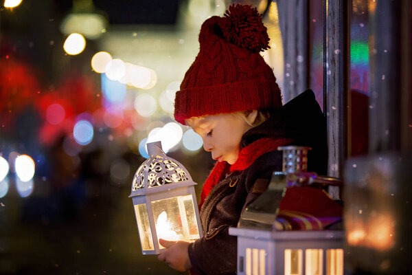 Sweet little toddler boy, holding lantern and a teddy bear at ni