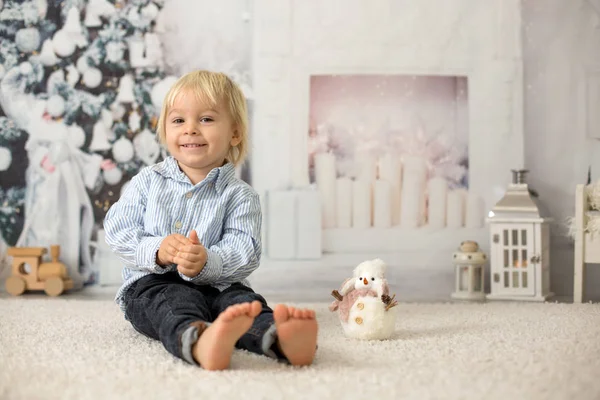 Blond toddler child, boy, reading a book at home, lying on the f — Stock Photo, Image
