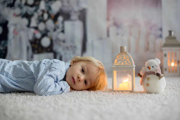 Dulce niño boylying en el suelo en casa con velas, waiting tin —  Fotos de Stock