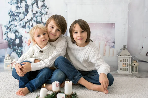 Three children, boy brothers, reading book at home at night on C — Stockfoto