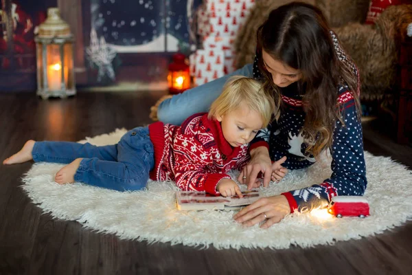 Счастливая улыбающаяся семья, мама и мальчик, читающие книги на Рождество — стоковое фото