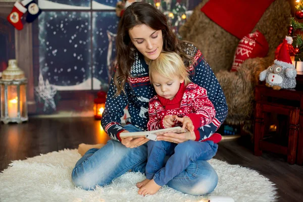Χαρούμενη χαμογελαστή οικογένεια, μαμά και αγόρι, διαβάζοντας βιβλία τα Χριστούγεννα — Φωτογραφία Αρχείου