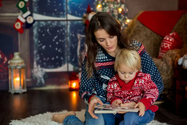 Χαρούμενη χαμογελαστή οικογένεια, μαμά και αγόρι, διαβάζοντας βιβλία τα Χριστούγεννα — Φωτογραφία Αρχείου
