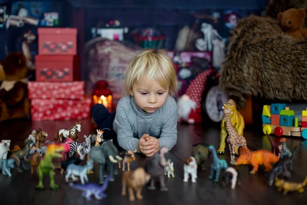 Милый блондин мальчик, играющий с пластиковыми животными и динозаврами — стоковое фото