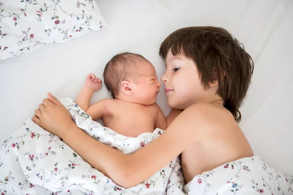 Schöner Junge, umarmt mit Zärtlichkeit sein neugeborenes Baby — Stockfoto
