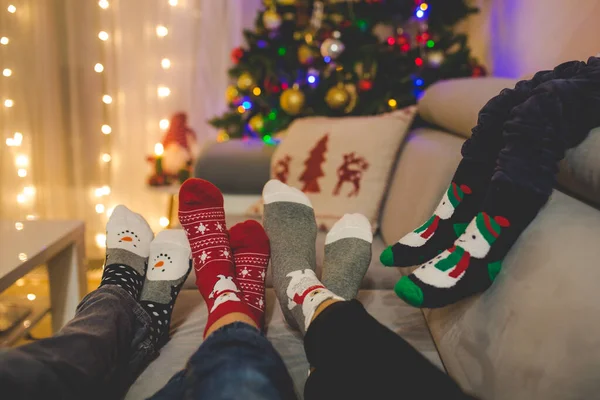 Vier Paar Füße in Weihnachtssocken, Mutter und Kinder liegen auf — Stockfoto