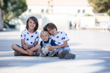 Üç sevimli çocuk, erkek kardeşler, yerde oturuyorlar. 