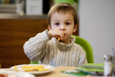 Küçük çocuk, abur cubur yiyor.