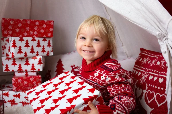 Lindo niño rubio con suéter de Navidad, regalos de apertura —  Fotos de Stock