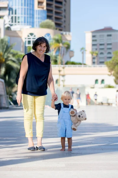 Cute child, toddler boy and grandmother,  walking hand in hand i — Stock Photo, Image