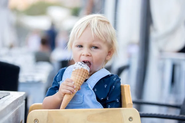 Маленький солодкий хлопчик, що їсть морозиво з конуса, сидить — стокове фото