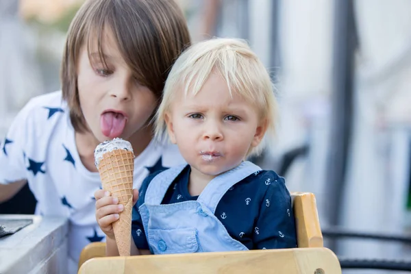 Маленький солодкий хлопчик, що їсть морозиво з конуса, сидить — стокове фото